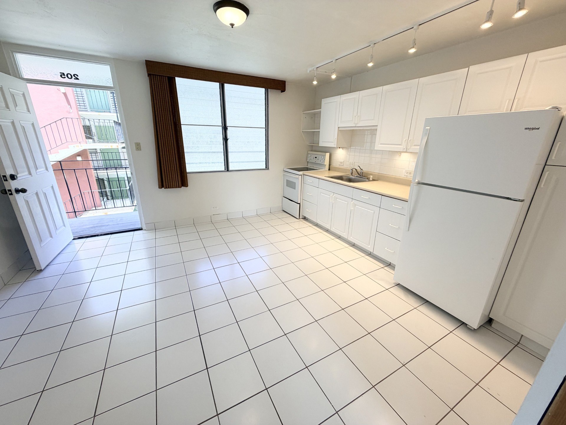 A kitchen with white appliances and white tiled floors.